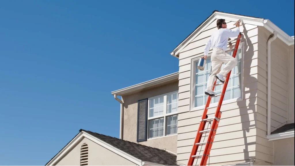Painter applying paint to exterior house siding