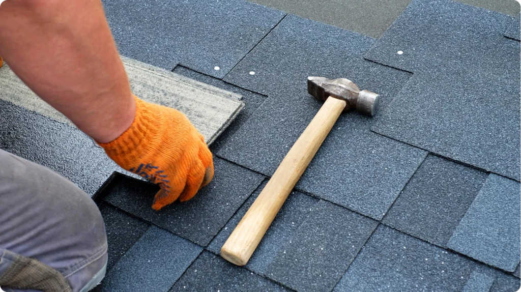 Roofer repairing asphalt shingles on residential roof